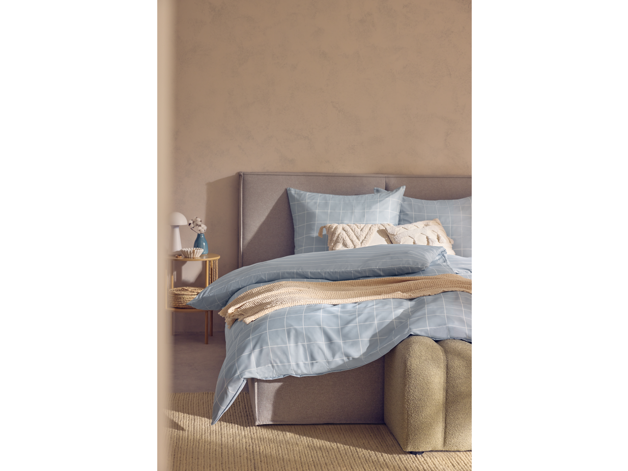 Livarno Microfibre Satin Bedlinen in light blue with a grid pattern, on a bed with a grey headboard.