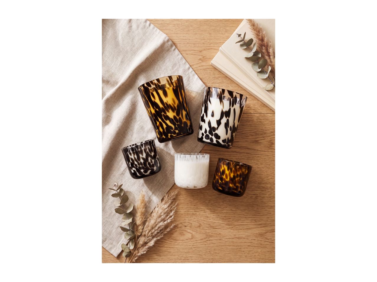A selection of stylish tortoiseshell and patterned glass candle holders on a wooden table.