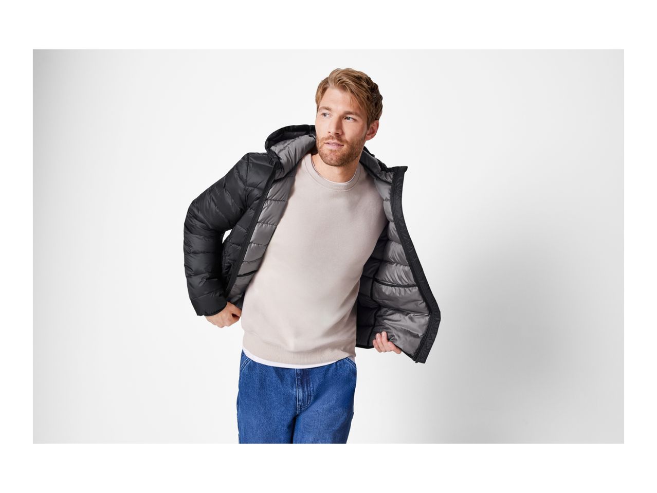 Man in a black puffer jacket, light sweatshirt, and blue jeans