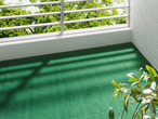 Green Artificial Grass Mat on a balcony overlooking trees.