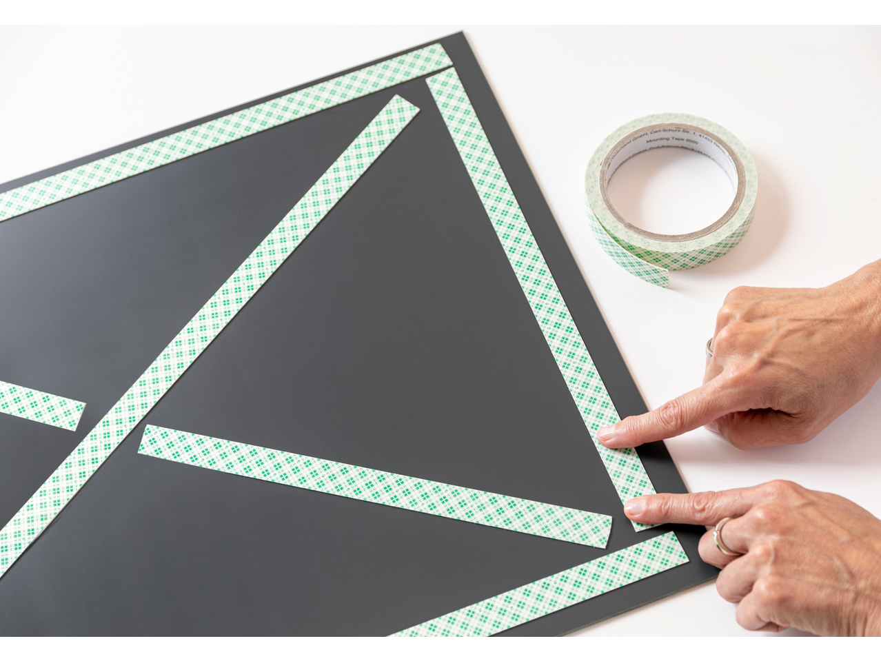 Bandă de montaj 3M pe panou negru, aplicată cu mâinile.