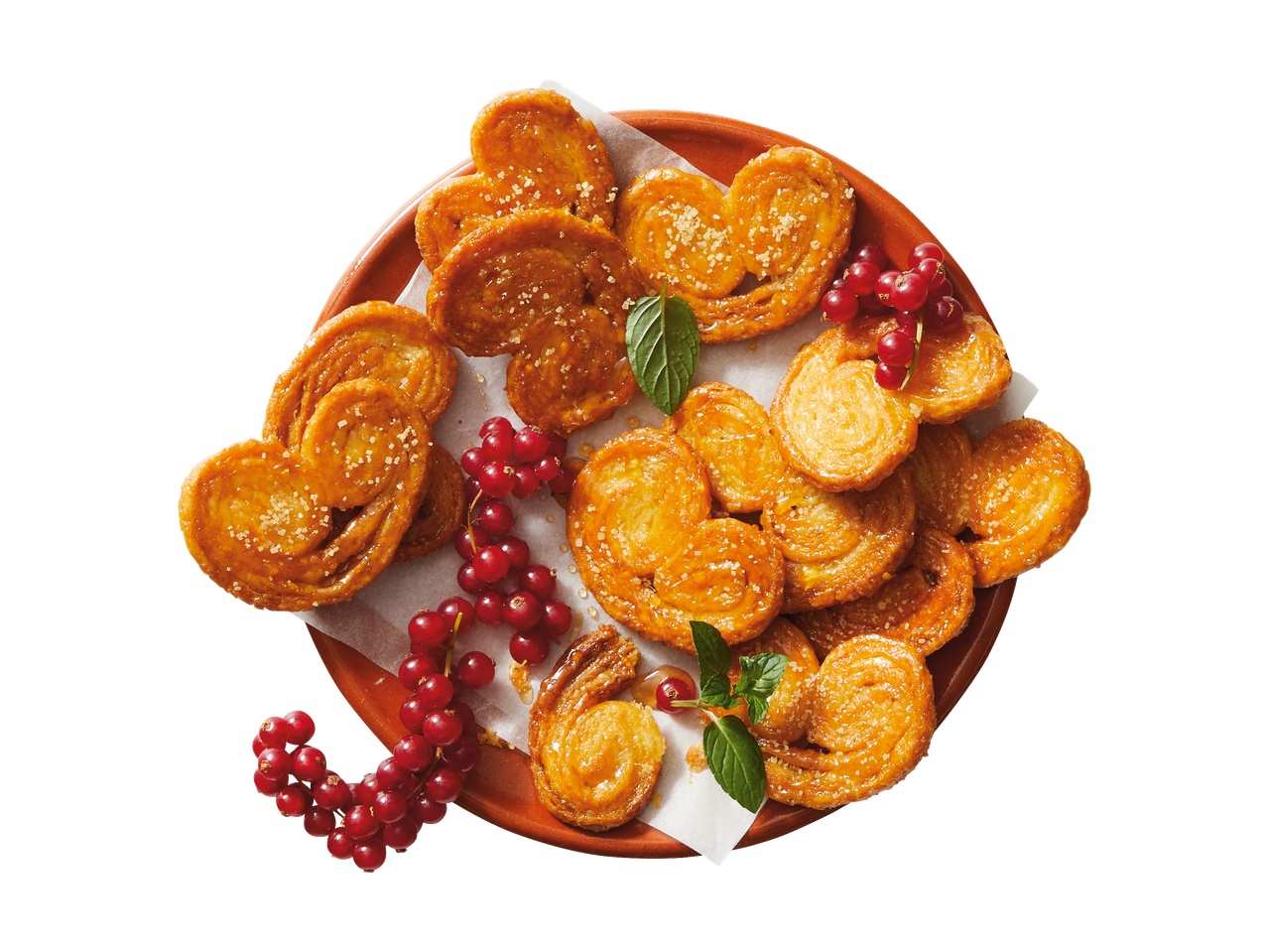 Sugar palmiers and red currants on a terracotta plate.