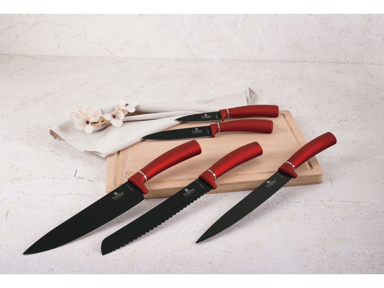A set of red-handled kitchen knives on a cutting board.