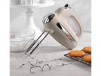 A beige retro-style hand mixer with beaters and dough hooks sits on a countertop next to freshly baked cookies.