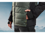 Crivit ski jacket, green and black, with hand in a zippered pocket.