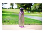 A purple reusable water bottle filled with water on a wooden table in a park.