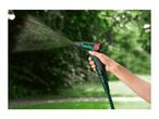 Hand holding a green garden hose nozzle spraying water in a garden.