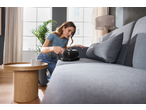 Femeie curățând o canapea gri cu un aspirator anti-acarieni SILVERCREST.