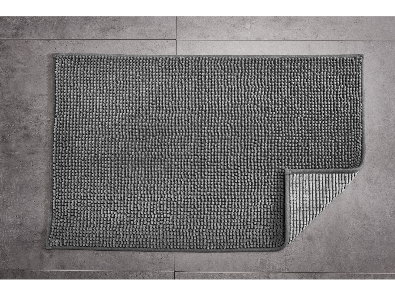 LIVARNO home gray bath mat with a corner folded back on a tiled floor.