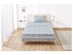 A light blue leaf-patterned bedsheet set on a single bed in a bright bedroom.