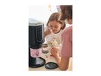 Two children enjoying ice cream with toppings, next to a dessert maker.