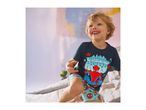 Smiling boy in a dark blue t-shirt and light blue shorts with a superhero print.