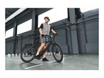 Man in cycling gear with a black e-bike in an industrial setting.