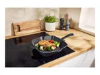 Grilled salmon and vegetables in a cast iron pan on an induction cooktop.