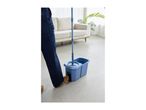 Person using a blue spin mop and bucket system on a light-colored floor in a living room.