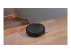 Robot vacuum cleaner on a wooden floor near a staircase.