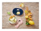 Lemon ice cream tub and bowls with lemon slices, mint, and puff pastry on a wooden table.