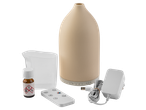 A beige essential oil diffuser with accessories: a measuring cup, remote, power adapter, and essential oil bottle.