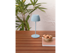 A light blue table lamp and a bowl of cookies on a wooden table outdoors.