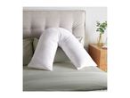 White V-shaped pillow on a bed with a grey headboard and green bedding.