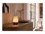 An elegant, glowing essential oil diffuser emitting mist on a wooden sideboard.