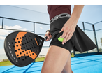Mulher com roupa desportiva CRIVIT, raquete de padel e bola num campo azul.