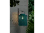 A teal outdoor lantern with a patterned design, casting light on a textured wall.