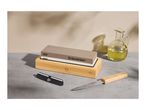 Whetstone on a bamboo base with a knife, knife sharpener, and oil bottle.