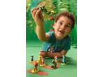 Uma criança brinca com figuras da Patrulha Pata e um dinossauro dourado numa superfície verde.
