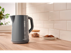 A SilverCrest gray electric kettle sits on a light wood countertop in a kitchen.