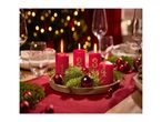 Advent wreath with four lit red candles, numbered 1 to 4, on a festive table.