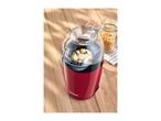 Red popcorn maker with popped corn, next to a jar of unpopped kernels on a wooden surface.