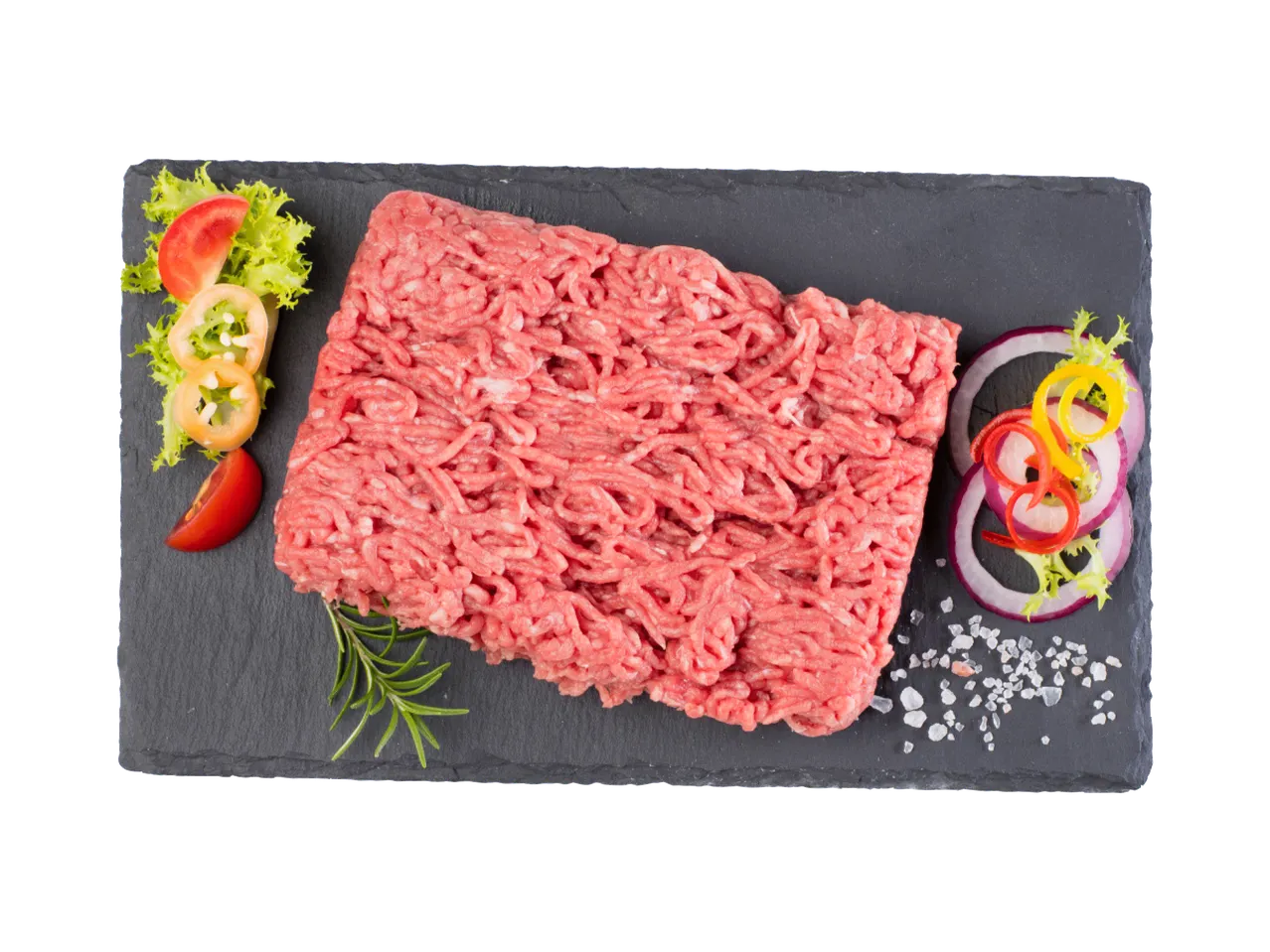 Sveže mleveno meso sa začinima i povrćem na crnoj ploči.