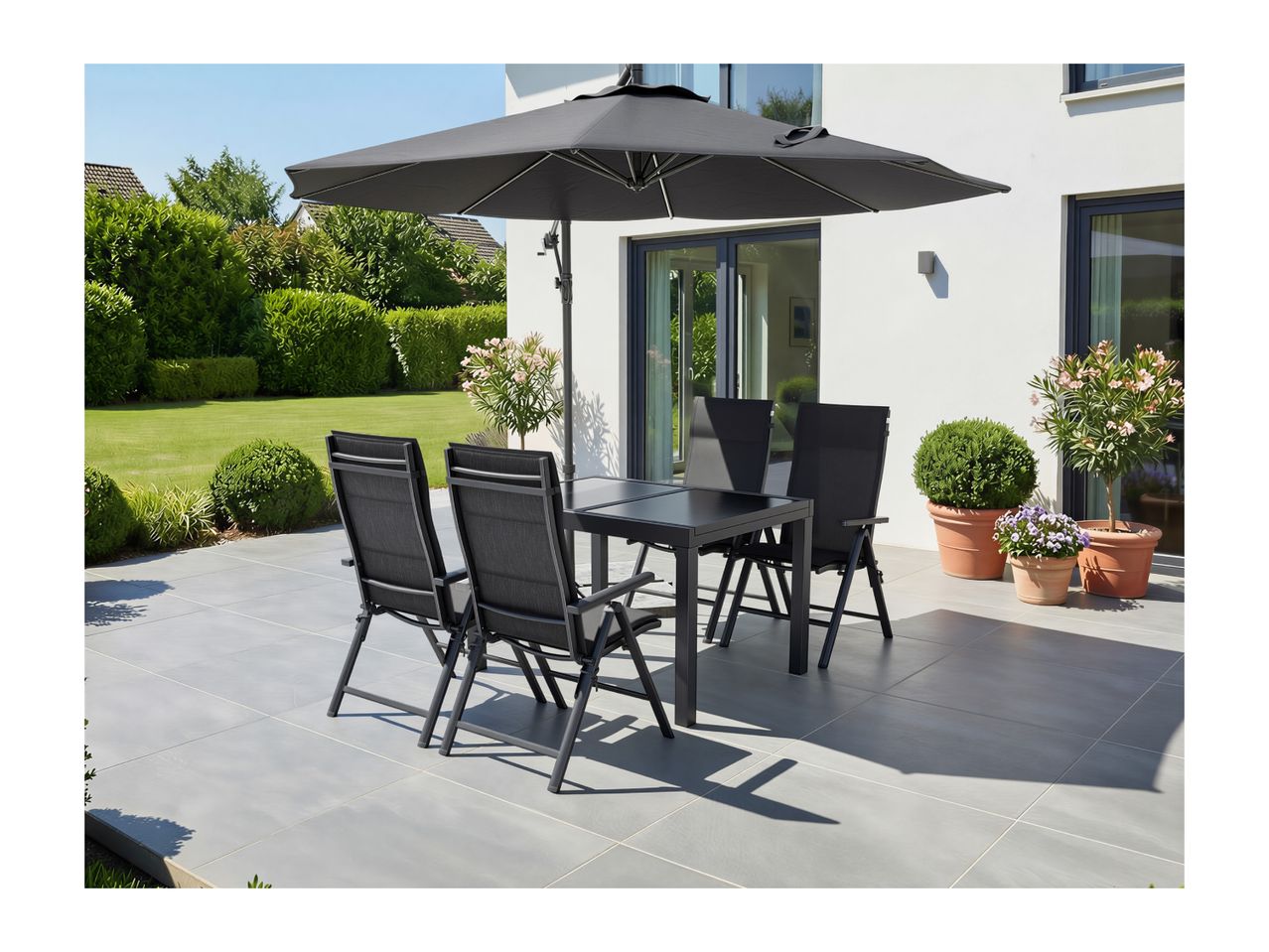 Patio dining set with black table and four chairs under a large black umbrella on a sunny day.
