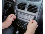 Mâini care folosesc unelte PARKSIDE pentru a scoate un radio auto din bord.
