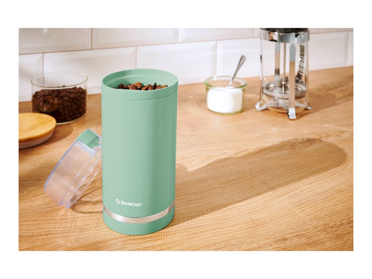 SilverCrest coffee grinder with coffee beans, sugar, and a French press.