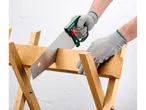Una persona che indossa guanti protettivi taglia un pezzo di legno con una sega su un cavalletto.