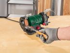 A person sharpening a chisel on a Parkside bench grinder.