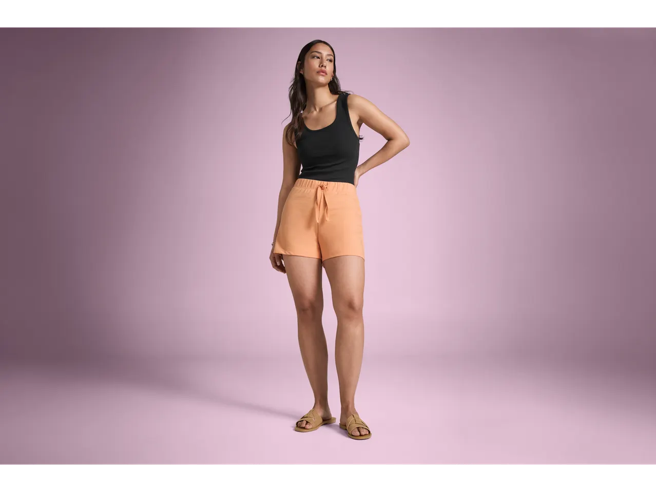 Model wearing orange shorts and a black tank top.
