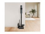 Cordless vacuum cleaner with accessories on a charging station in a modern living room