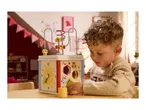 A young child plays with a wooden activity cube featuring a bead maze, clock, and shape sorter.