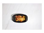 Roasted chicken with vegetables in a black roasting pan on a marble background