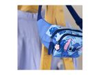 Blue fanny pack with a cartoon character and tropical leaf print, hanging on a wooden rack.