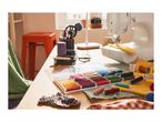 A sewing machine and a clear box of colorful thread spools on a wooden table.