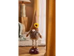 A decorative gnome with a sunflower on its hat stands on a wooden floor.
