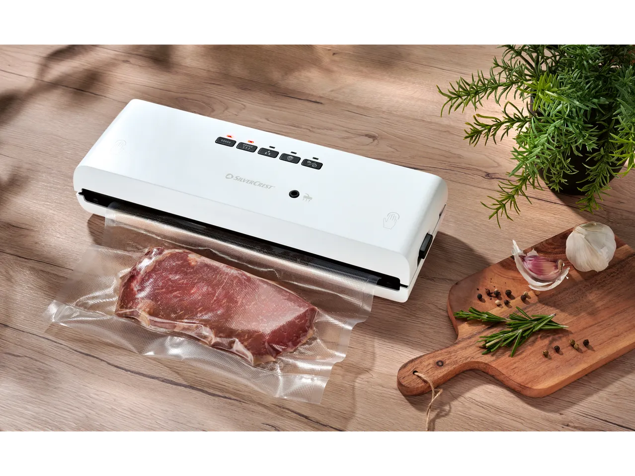 SILVERCREST® Vacuum Sealer with meat, garlic, rosemary, and peppercorns on a wooden board.