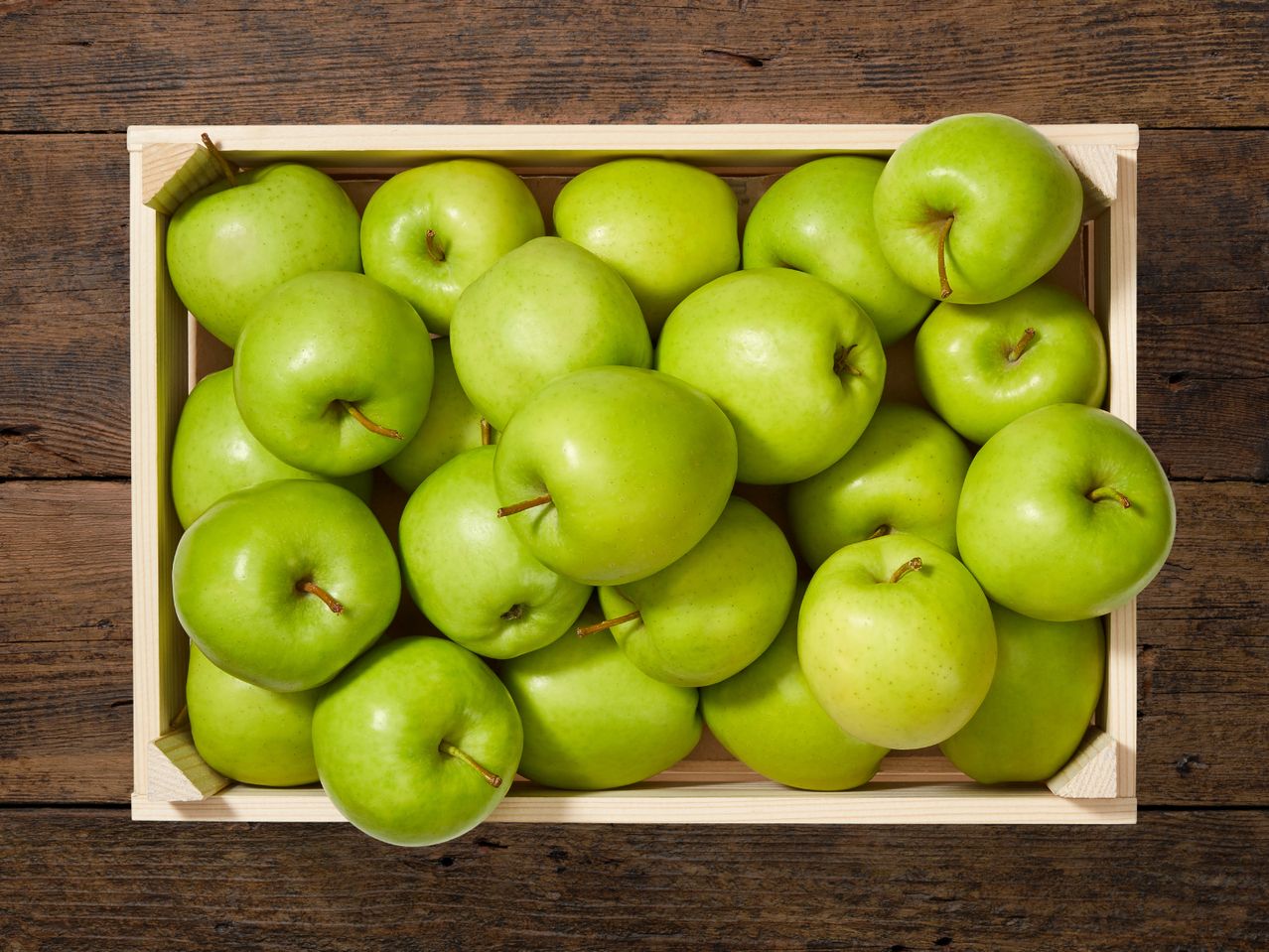 Eine Holzkiste voller grüner Äpfel.