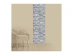 Beige armchair with a cushion next to a wall with a vertical grey stone pattern.