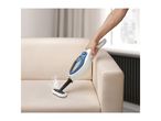 Handheld steam cleaner cleaning a beige sofa, with steam visible.