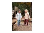 Two happy children in waterproof jackets and trousers splashing in a puddle.
